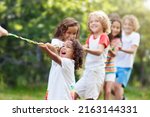Small photo of Kids play tug of war in sunny park. Summer outdoor fun activity. Group of mixed race children pull rope in school sports day. Healthy outdoor game for little boy and girl.