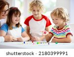 Small photo of Family playing board game at home. Kids play strategic game. Little boy throwing dice. Fun indoor activity for summer vacation. Siblings bond. Educational toys. Friends enjoy game night.