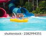 Kids on water slide in outdoor swimming pool. Family in aqua theme park. Children have fun in splash playground. Summer vacation with child. Kid on inflatable tube sliding into a pool.