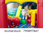 Child jumping on colorful playground trampoline. Kids jump in inflatable bounce castle on kindergarten birthday party Activity and play center for young child. Little girl playing outdoors in summer.