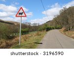 A country road in the Elan Valley, Wales with a sheep warning sign.