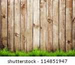 Fresh spring green grass over wood fence background