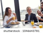 Group of business people having breakfast in company's restaurant. Focus on the woman on the left