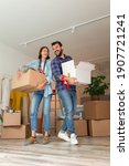 Small photo of Couple in love moving in together, having fun while carrying cardboard boxes filled with their possessions and setting up the new apartment