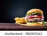 Craft beef burger and french fries on wooden table isolated on black  background.