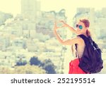 Young beautiful woman in San Francisco making hand shaped heart on spring summer warm sunny day. Girl with sunglasses happy outdoors. Instagram style image with yellow filter