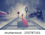Young beautiful woman in red dress waiting old train on the platform of railway station. Dreamy foggy screen saver. Retro style vintage Instagram picture. Vacation voyage getaway adventure concept 