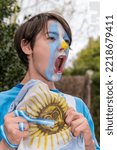 Small photo of Fanatic boy of the Argentine national team. Cheering for the team with his face painted in the colors of Argentina.