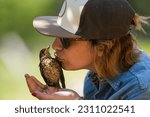 Woman kissing a little bird after being recovered from the ground when it fell from its nest.
