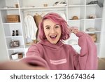 Small photo of Excited hipster gen z teen girl fashion social media channel blogger stylist with pink hair piercing wear hoodie look at camera record vlog video tutorial in front of clothes wardrobe, face headshot.