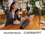Small photo of Doubtful Asian young adult business woman talking on cell phone making call working looking away thinking of solution sitting in cafe, considering offer, making decision or feeling doubt.