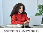 Small photo of Young happy latin business woman employee using laptop, having remote virtual work meeting call in office or watching webcast online webinar training web course looking at computer sitting at desk.