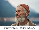 Small photo of Happy older bearded man standing in nature park enjoying landscape. Smiling active mature traveler looking away exploring camping tourism nature mountains view feeling freedom. Close up portrait