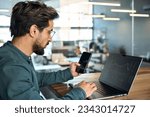 Stock trader investor broker holding mobile phone looking at laptop using computer analyzing trade cryptocurrency financial digital market indexes crypto stockmarket charts data, side view.