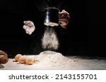 Small photo of woman sifts flour through sieve onto table with eggs on a black background. the concept of homemade baking and cooking school. recipes for bread, pizza and pies. family business. professional bakery.