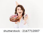 Small photo of a lilt woman with a glass of champagne and a birthday cake with candles on a white background. traditional sweet treat and wish-making for a birthday.