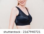 Small photo of A young woman in black compression underwear after mammoplasty. corset during the rehabilitation period after plastic surgery. postoperative clothing.