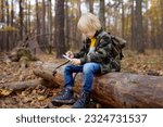 Small photo of Little boy scout is sharpening a stick with the help knife in the forest. Concepts of adventure, scouting and hiking tourism for kids.