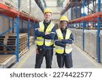 Small photo of Two warehouse workers smile happily at the camera as they stand in the aisle in their work clothes. In a cheerful manner working together in a large distribution center.