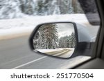 Side view mirror reflection of Snow-covered road in forest