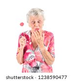 Small photo of Excited old woman holding amiss photo booth prop with her eyes closed against a white background