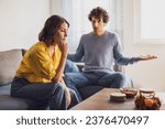 Small photo of Man and woman are sitting at sofa and arguing. Relationship problems.