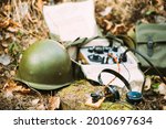 Russian Soviet Portable Radio Transceiver Used By USSR Red Army Signal Corps In World War Ii. Headphones, Telegraph Key And Helmet Are On A Forest Stump.