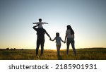 Small photo of people in the park. happy family walking silhouette at sunset. mom dad and daughters walk holding hands in the park. happy family childhood dream concept. sun parents and children go back silhouette