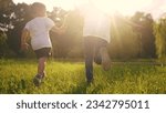 Small photo of children run in the park. boy and a girl holding hands run through the grass in the summer at sunset in the park. happy family kid dream concept. children run at sunset in summer hold hands sun
