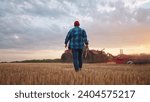 Small photo of agriculture. farmer walk works in a field next to a tractor that plows the land. business agriculture concept. farmer with tablet works in field next to a tractor at farm sunset mowed wheat plows