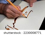 Small photo of A calligrapher writing with pen and ink. man hands writing arabic calligraphy with ink. Arabic and Persian calligraphy. Writing Nastaliq calligraphy. "Help me" written in Arabic