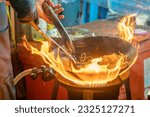 Small photo of fried noodles cook in pan with big fire flame is hong kong style. Pad Thai favorite and famous Asian Thai street fast food in hot pan, Pad Thai is fried rice noodle dish a street food Thailand