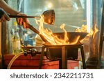 Small photo of fried noodles cook in pan with big fire flame is hong kong style. Pad Thai favorite and famous Asian Thai street fast food in hot pan, Pad Thai is fried rice noodle dish a street food Thailand