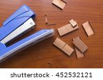 Blue stapler and piles of copper office staples on wooden office, closeup, top view