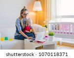 Small photo of Stay at home mom working on laptop with kid on her lap