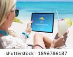 Woman viewing weather forecast on tablet while relaxing on the beach
