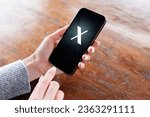 Person holding mobile phone with a letter X on the screen