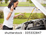 Woman standing next to broken car and talking on the phone 