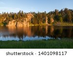 Golden sunshine in the late afternoon shines on a quartz rock formation and creates a soft reflection at Stockade Lake in Custer State Park, South Dakota.
