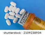 Small photo of Hydrocodone tablets with a hundred dollar bill and a pill bottle. Opiate addiction costs the U.S. economy $78.5 billion per year.