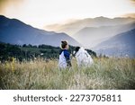 woman looking at sunset over hills with her dog