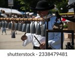 Small photo of KEZMAROK, SLOVAKIA - JUL 9, 2023: Handicraftsman plays on handmade cowbells at The European Folk and Crafts Festival in Kezmarok, Slovakia