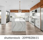 Small photo of Beautiful kitchen in new luxury home with large waterfall island, stainless steel appliances, pendant lights, gorgeous backsplash and cabinets.