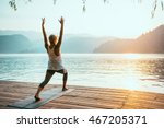 Beautiful woman practicing Yoga by the lake - Sun salutation series - Virabhadrasana - Toned image