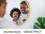 Small photo of Portrait of happy family black African American father and son child boy brushing teeth in the bathroom. Morning routine with toothbrushes, fatherâ€™s day concept