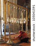 Small photo of Temple of the Holy Sepulcher in Jerusalem. The oldest Christian sanctuary - Stone of Unction. The pilgrim in red clothes passionately prays under icon lamps.