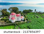 Small photo of Tropical park. Pink domes with golden crosses of the Greek Orthodox monastery of the Twelve Apostles in Capernaum. Israel