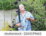Senior or elderly man holding a folding umbrella and looking up at the sky to see if it is going to rain.