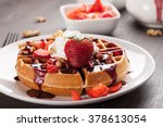 Whole wheat Belgium waffle topped with boysenberry syrup, whipped cream, walnuts, and freshly chopped strawberries horizontal shot