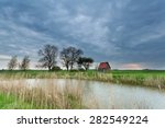 little house on meadow by river and clouded sky